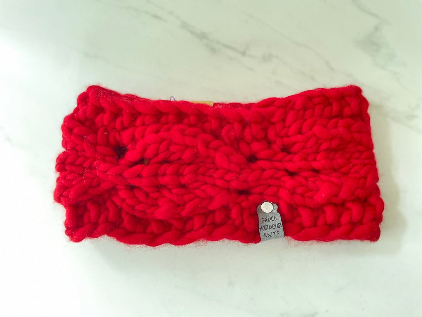 Red knitted headband with a brand tag on a white background