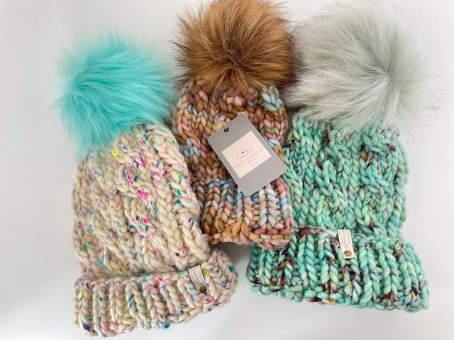 Colorful knitted hats with pom-poms on a white background