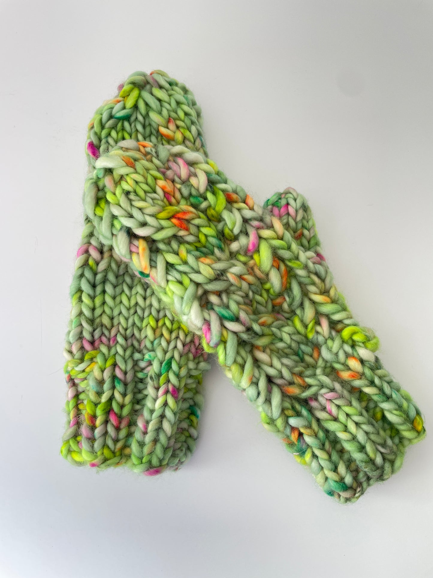 Green knitted mitts with multicolor pattern on a white background