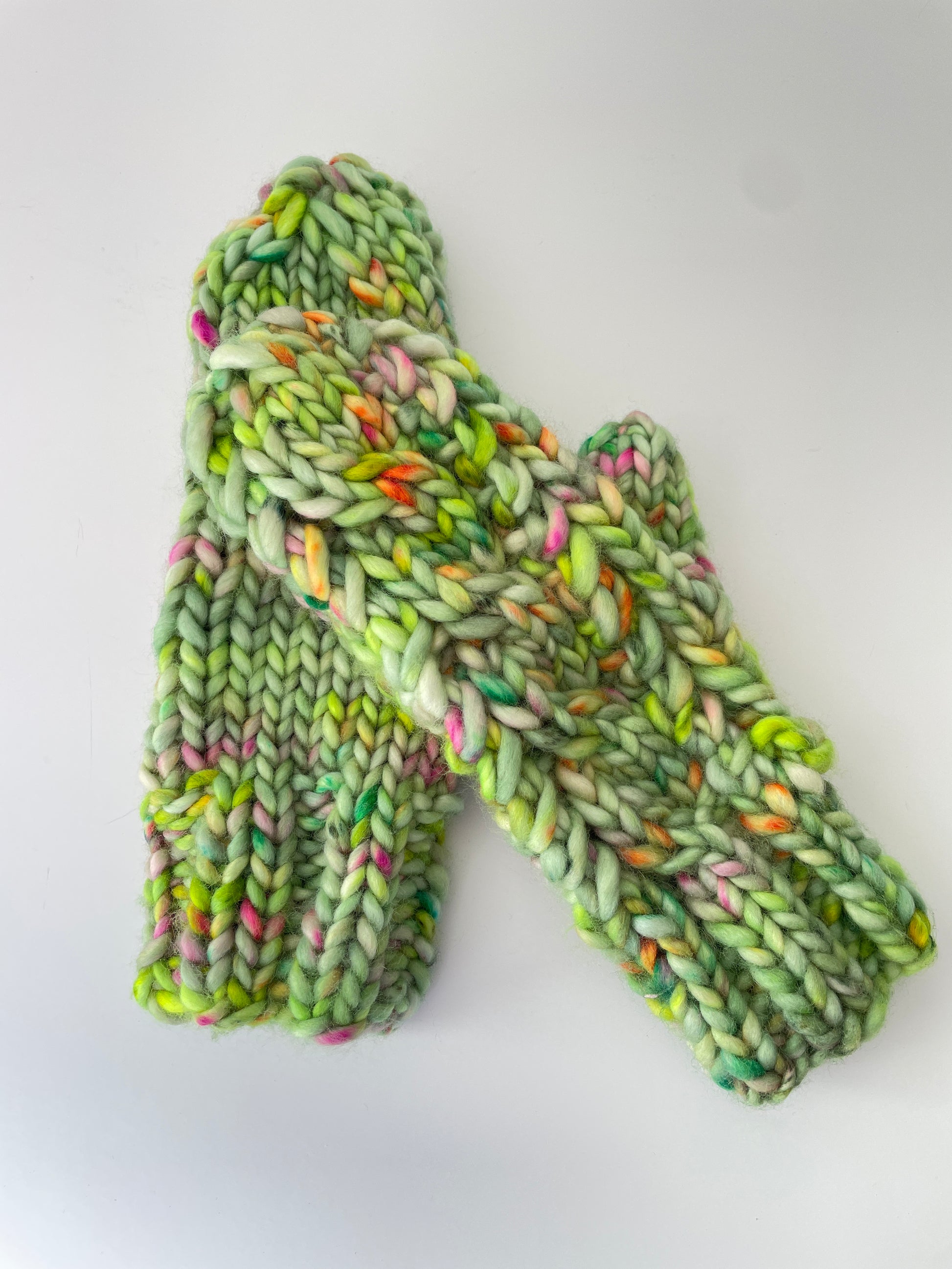 Green knitted mitts with multicolor pattern on a white background
