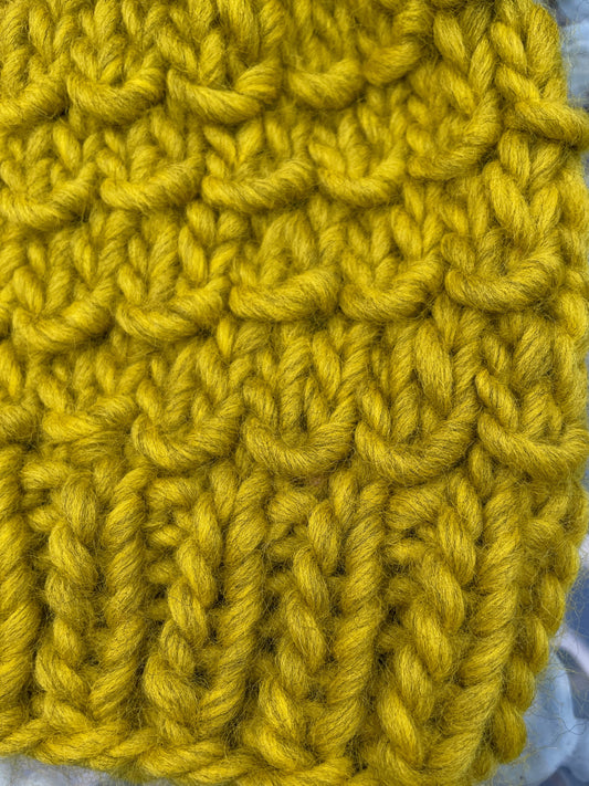 Close-up of yellow knitted fabric on a textured surface