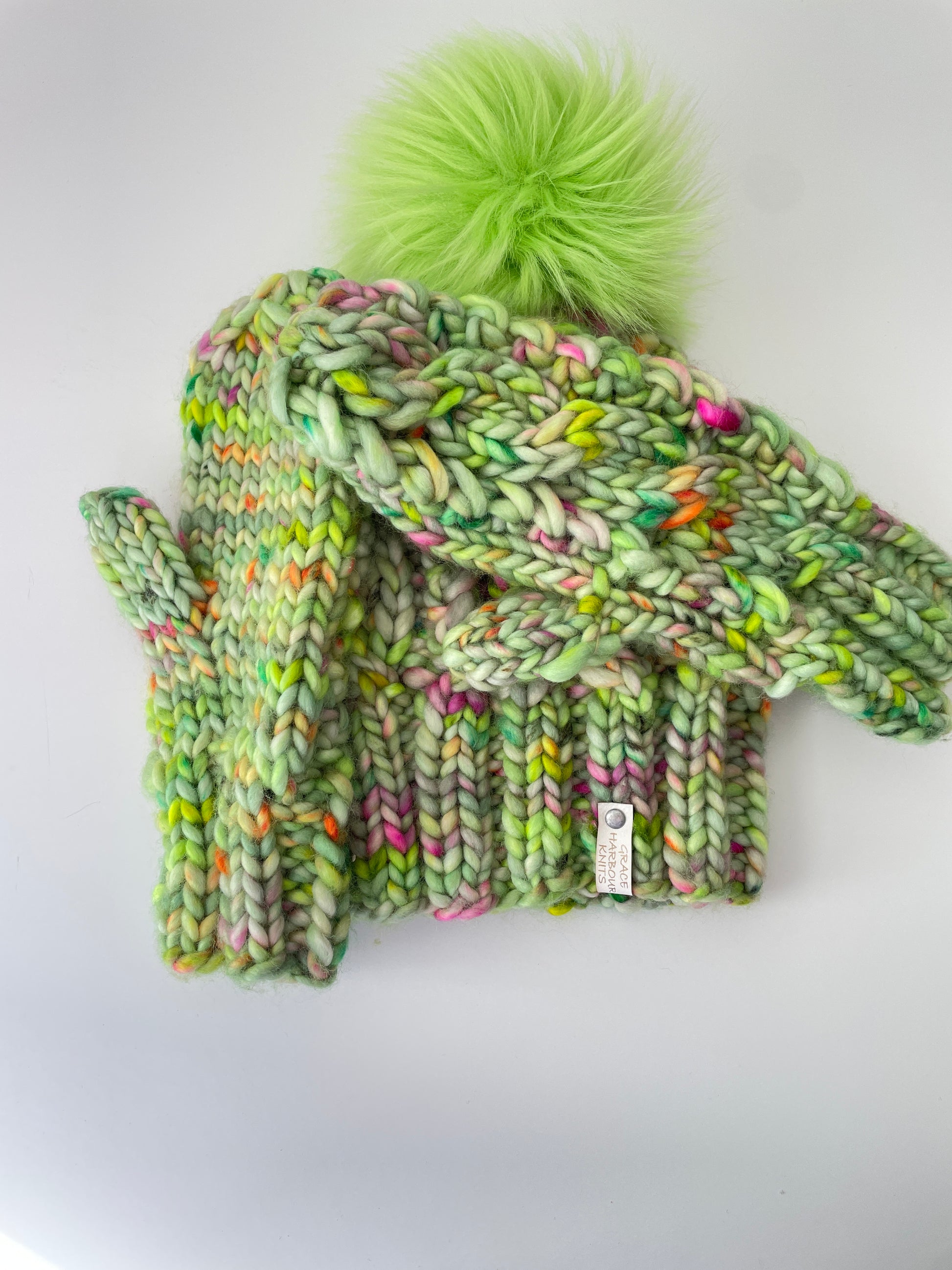 Green knitted hat and mittens set with a pom-pom on a white background