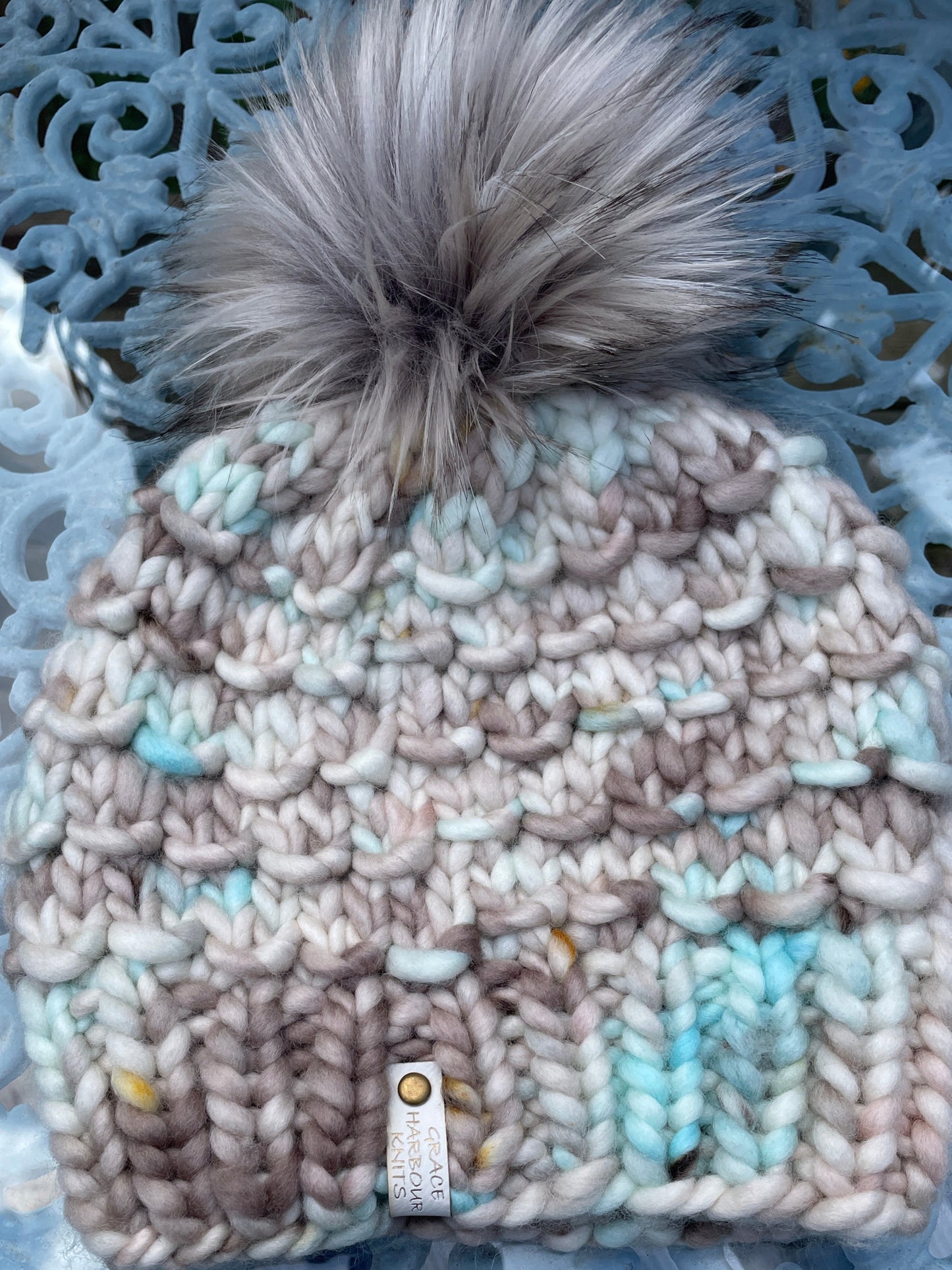 Knitted beanie with a fluffy pom-pom on a textured surface